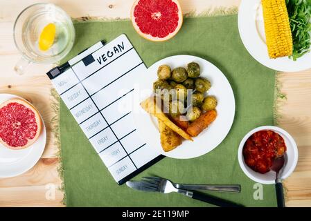 Vue de dessus plats à base de plantes avec maquette pour le menu vegan hebdomadaire. Portion de repas de légumes cuits comme choux de bruxelles, racine de persil, carottes, maïs Banque D'Images