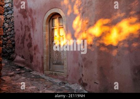 Porte et mur en bois d'une vieille maison avec texture et couleurs intéressantes baignées dans la lumière du soleil de l'aube, Monemvasia, Grèce Banque D'Images