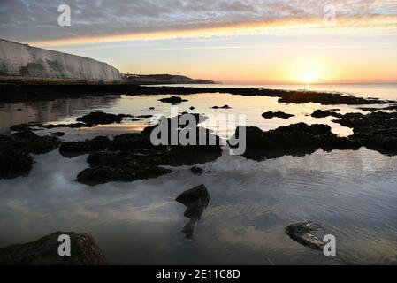 Soleil incandescent sur le rivage rocheux avec un ciel serein et des eaux réfléchissantes près de Rottingdean, East Sussex, Angleterre, Royaume-Uni Banque D'Images