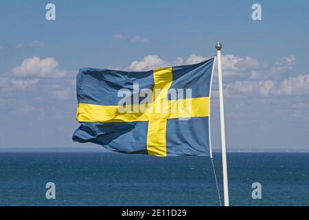 Le drapeau suédois flotte dans le vent devant le bleu Ciel nuageux Banque D'Images