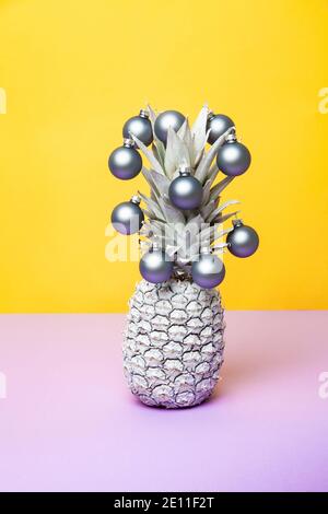 Ananas blanc décoré de boules de Noël sur fond jaune Banque D'Images