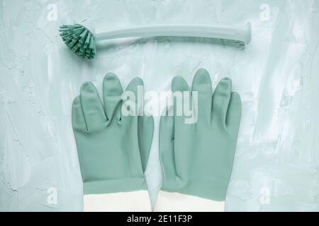 Brosse et gants de vaisselle sur fond vert Banque D'Images