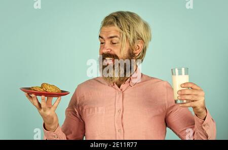 lait et biscuits. happy farmer mange des biscuits dessert. l'homme barbu boimerie avec de la pâtisserie. Le concept de saine alimentation. Produits agricoles biologiques pour le petit déjeuner ou le déjeuner. Banque D'Images