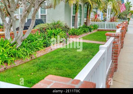 Cour avant de la maison avec allée verte clôture en bois et des poteaux en brique rouge Banque D'Images