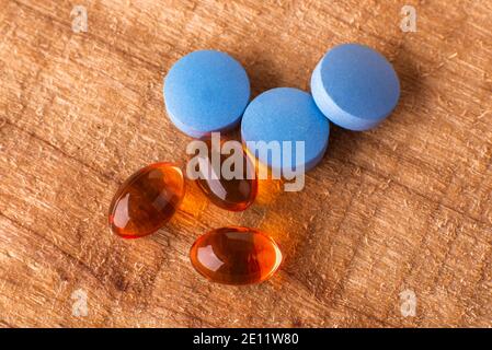 Pilules orange et pilules bleues sur fond en bois isolé Banque D'Images