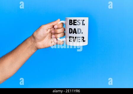 Main de l'homme hispanique tenant le meilleur papa jamais tasse de café sur fond bleu isolé. Banque D'Images