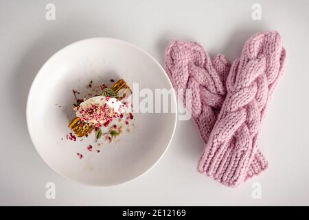 Moufles roses et gâteau sur table en bois blanc. Arrière-plan de Noël et du nouvel an. Vue de dessus, espace de copie. Composition confortable. Couche plate d'hiver. Banque D'Images