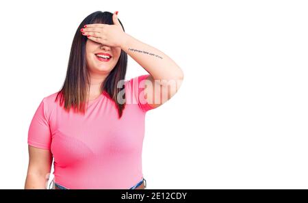 Jeune femme de taille plus portant des vêtements décontractés souriant et riant avec la main sur le visage couvrant les yeux pour la surprise. Concept aveugle. Banque D'Images