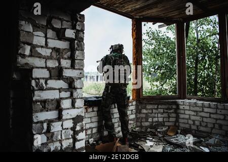 Un militaire avec une affaire d'arme à feu prend un fusil d'assaut dans la ville détruite. Concept d'opération militaire et de sauvetage. Banque D'Images