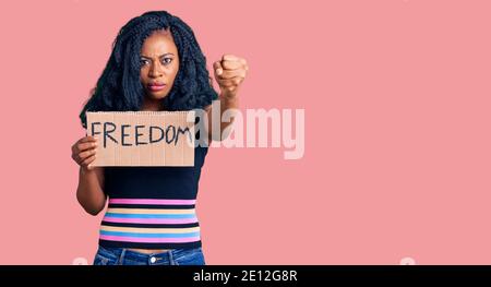 Belle femme afro-américaine tenant la bannière de liberté agacée et frustrée criant avec colère, hurlant fou avec la colère et la main levée Banque D'Images