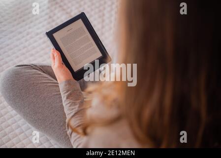 Femme lisant un livre électronique assis sur le lit. Concept pour l'étude, la lecture Banque D'Images