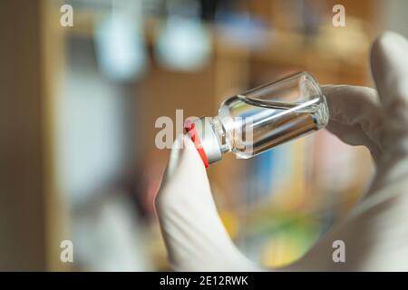 Une bouteille de vaccin dans une main avec un gant Banque D'Images