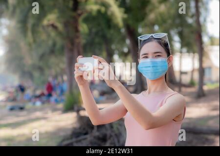 Les femmes asiatiques portent un masque médical voyage sur la mer de plage Thaïlande, les nouveaux thaïlandais normaux Voyage en Thaïlande Banque D'Images