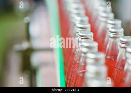 Les bouteilles de boisson sont transportées sur un convoyeur dans un usine de production Banque D'Images