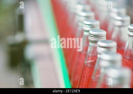 Les bouteilles de boisson sont transportées sur un convoyeur dans un usine de production Banque D'Images