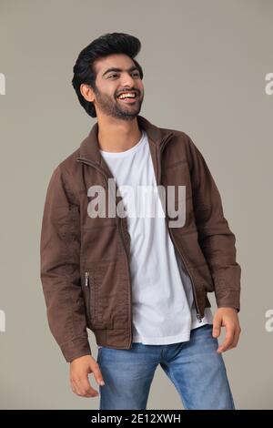 UN JEUNE HOMME REGARDANT LE CÔTÉ ET RIANT Banque D'Images