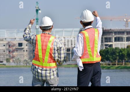 Un ingénieur tient un plan pour l'usine de construction dans une zone industrielle. Banque D'Images