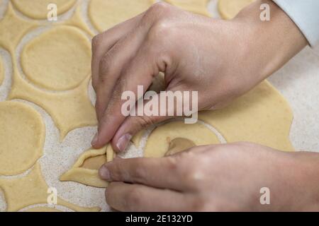 Hamantaschen. (Ozenei haman) pâte triangulaire à base de pâte croustillante, farcie de pavot, d'halva ou de chocolat. Pour les vacances juives de Purim. Mains dans Banque D'Images