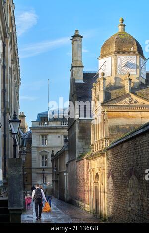 Un étudiant avec ses promenades de shopping le long du passage de la Maison du Sénat, passant par la porte d'honneur, avec sa coupole et son cadran solaire, à Gonville et Caius College, Banque D'Images