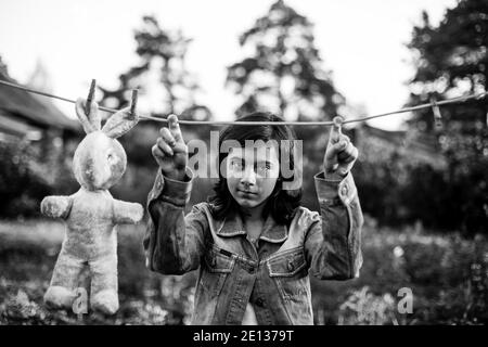 Une jeune fille sèche un lièvre sur une corde à linge. Photo en noir et blanc. Banque D'Images