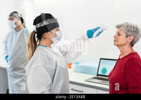 Femme médecin mesurant la température des patients âgés pour la maladie du coronavirus - Concentrez-vous sur la bonne femme Banque D'Images