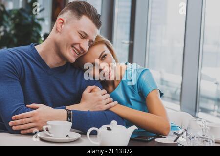 Couple amoureux heureux en cuddling au café, espace de copie. Beau homme joyeux souriant avec ses yeux fermés en appréciant le petit déjeuner avec sa petite amie. Beaut Banque D'Images