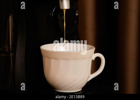 Une tasse de café est versée dans la machine à café Banque D'Images