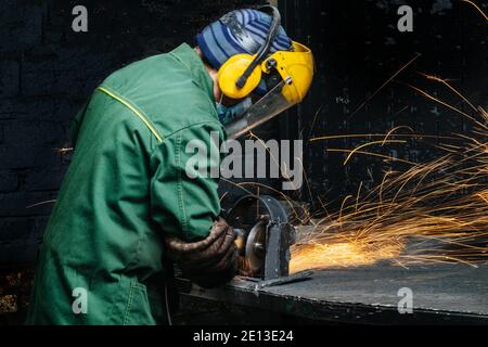 travailler avec une meuleuse d'angle à la main, dans des vêtements de protection spéciaux Banque D'Images