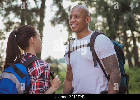 Beau homme africain riant, appréciant voyager avec sa petite amie. Couple de randonnée dans la forêt. Un homme sympathique qui parle à son woma Banque D'Images