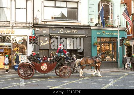 Le Père Noël à cheval en calèche de Noël pour les enfants dans le centre-ville de Dublin. Banque D'Images