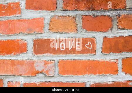 Fond de mur en brique rouge avec inscription D'AMOUR Banque D'Images