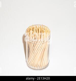 Cure-dents en bois dans un pot en plastique isolé sur fond blanc Banque D'Images