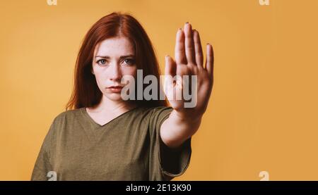 une jeune femme sérieuse fait un geste d'arrêt ou d'arrêt avec elle côté gauche Banque D'Images