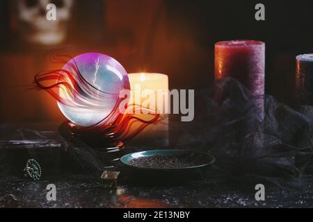 Boule de cristal de la fortune de teller, bougies et soucoupe avec des terres de café passé sur la table Banque D'Images