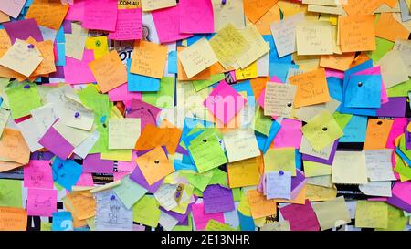 Collection de post-its colorés sur un mur avec différents textes sur elle Banque D'Images