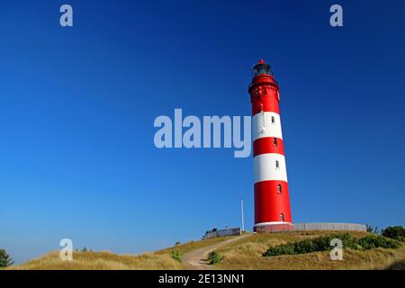 Phare à rayures blanches rouges sur l'île d'Amrum Allemagne un jour ensoleillé avec un ciel bleu dans les dunes Banque D'Images