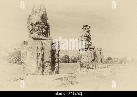 C'est le site archéologique 1350BC au Colossi de Memnon de l'Égypte ancienne, non loin du Nil et de la ville de Louxor connu auparavant sous le nom de Thèbes. Les statues sont du Pharaon Amenhotep III, il y a deux petites statues à ses pieds, l'une étant sa mère, l'autre son épouse. Initialement construit pour protéger l'entrée du temple d'Amenotep contre le mal, ils ont également été vus pour protéger la rive ouest du Nil. Les Colossi ont subi des dommages importants après le tremblement de terre, mais après 3500 ans, ils restent debout. Banque D'Images