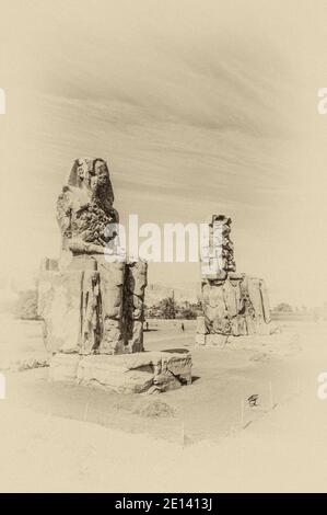 C'est le site archéologique 1350BC au Colossi de Memnon de l'Égypte ancienne, non loin du Nil et de la ville de Louxor connu auparavant sous le nom de Thèbes. Les statues sont du Pharaon Amenhotep III, il y a deux petites statues à ses pieds, l'une étant sa mère, l'autre son épouse. Initialement construit pour protéger l'entrée du temple d'Amenotep contre le mal, ils ont également été vus pour protéger la rive ouest du Nil. Les Colossi ont subi des dommages importants après le tremblement de terre, mais après 3500 ans, ils restent debout. Banque D'Images