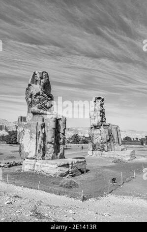 C'est le site archéologique 1350BC au Colossi de Memnon de l'Égypte ancienne, non loin du Nil et de la ville de Louxor connu auparavant sous le nom de Thèbes. Les statues sont du Pharaon Amenhotep III, il y a deux petites statues à ses pieds, l'une étant sa mère, l'autre son épouse. Initialement construit pour protéger l'entrée du temple d'Amenotep contre le mal, ils ont également été vus pour protéger la rive ouest du Nil. Les Colossi ont subi des dommages importants après le tremblement de terre, mais après 3500 ans, ils restent debout. Banque D'Images