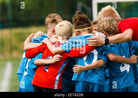 Groupe d'enfants en caucus avec l'entraîneur. Photo de groupe de l'équipe de football des jeunes. Enfants jouant aux sports d'équipe. Des garçons heureux joueurs de football coup de pied Banque D'Images