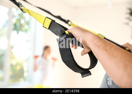 Jeune homme sportif s'entraîner avec des sangles TRX en salle de sport, en gros plan Banque D'Images