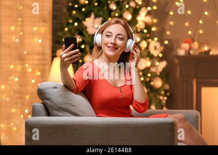 Femme adulte écoutant de la musique de Noël à la maison à Noël veille Banque D'Images