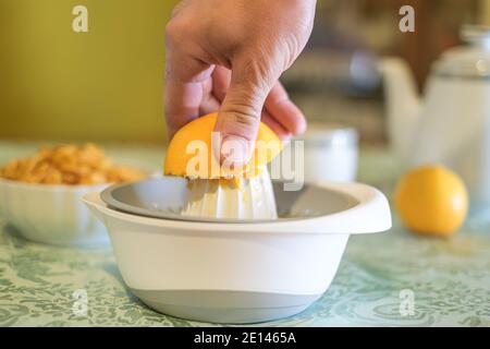 Homme pressant des fruits d'orange frais à la centrifugeuse, petit déjeuner sain, régime du matin Banque D'Images