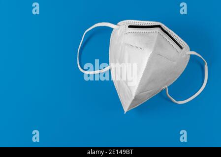 Masque blanc KN95 ou FFP2 sur fond bleu. Masque médical pour la protection Covid-19 pour prévenir la pandémie du coronavirus Banque D'Images