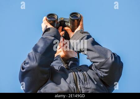 Jeune femme regardant dans des jumelles Banque D'Images