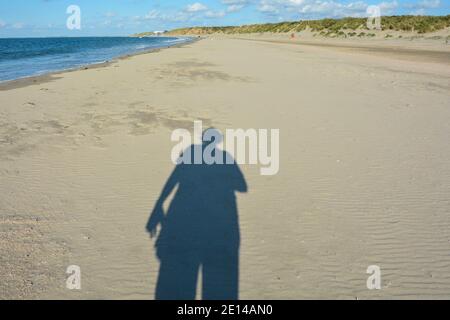 Ombre d'une personne sur la plage de sable à côté de la mer par une journée ensoleillée Banque D'Images