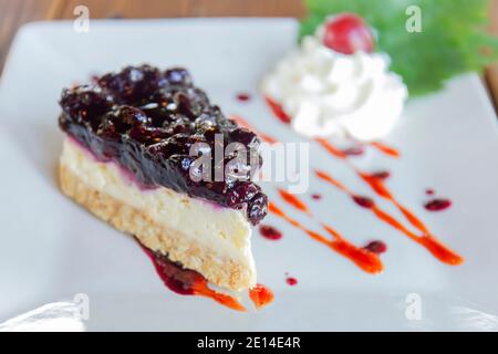 Le cheesecake aux myrtilles est disposé dans une belle assiette sur fond de table en bois. Banque D'Images