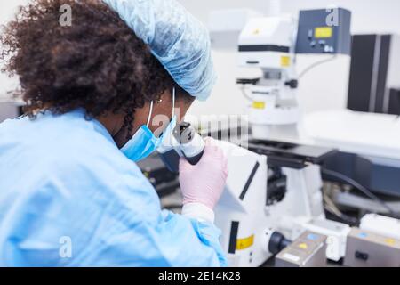 Le chercheur travaille au microscope en laboratoire dans le domaine de la pandémie Covid-19 pour un vaccin Banque D'Images