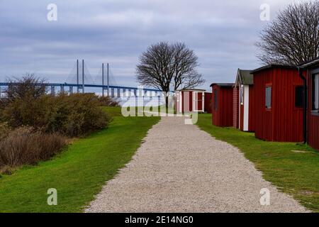 Cabanes de pêche rouges avec un pont et un océan bleu et des nuages sombres en arrière-plan. Photo de Malmö, sud de la Suède Banque D'Images