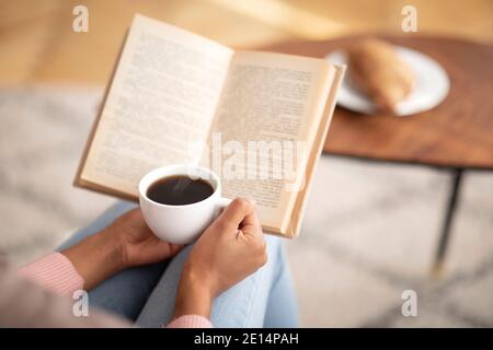 Dame noire méconnue avec livre de lecture de café, appréciant le matin paisible à la maison, espace libre Banque D'Images